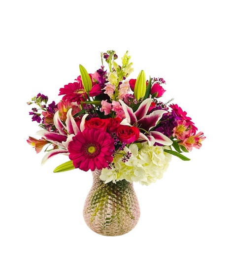 Bouquet of white hydrangea, gerbera daisies, pink roses, and stargazer lilies in a pink glass textured vase